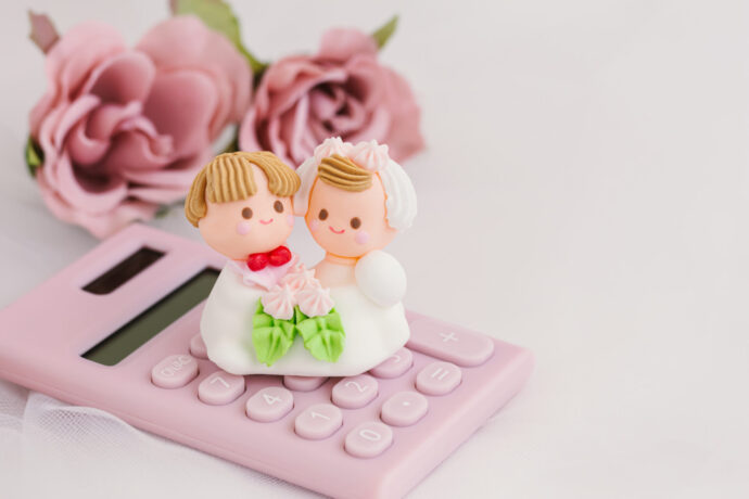 画像：ピンクの電卓とバラ、デフォルメされた花嫁と花婿の人形