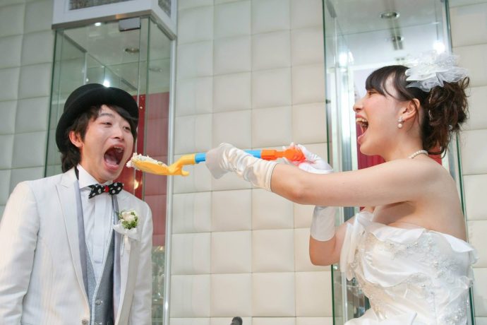 画像：スコップでファーストバイトを行う新婦と大口開けた新郎