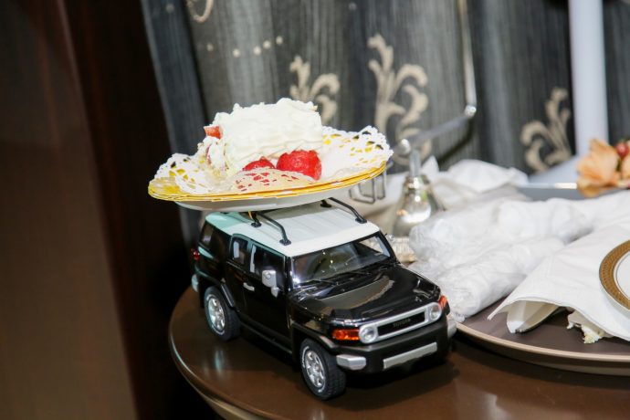 画像：黒い車のおもちゃに載せられた一切れのウエディングケーキ