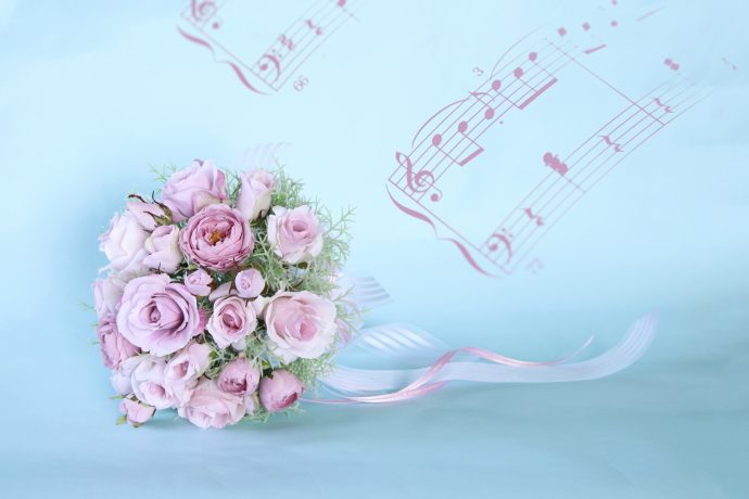 画像：ピンクベースの花束と水色の背景、壁には楽譜が描かれている