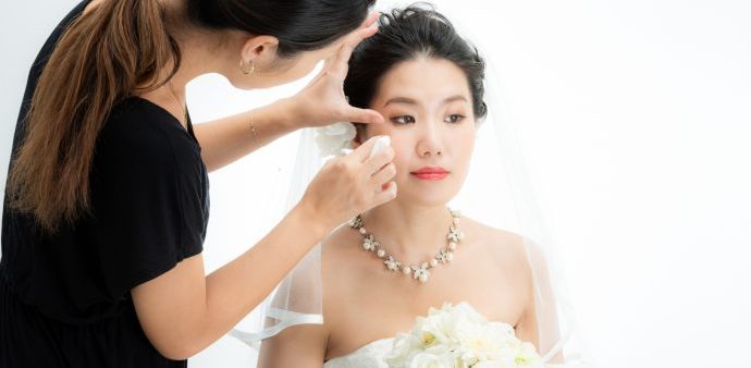 画像：メイキストにメイクを施されている花嫁