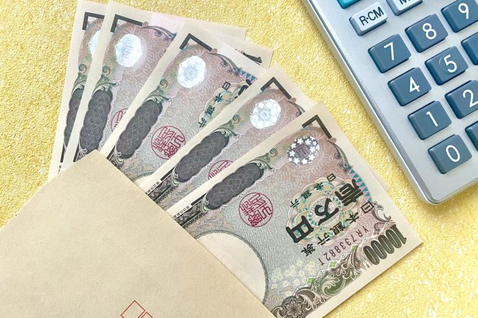 封筒からはみ出た1万円札と電卓の写真