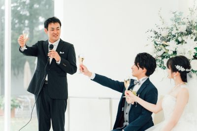 乾杯の挨拶をする男性と新郎新婦の写真