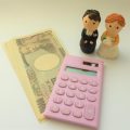 電卓と一万円札と新郎新婦の人形の写真