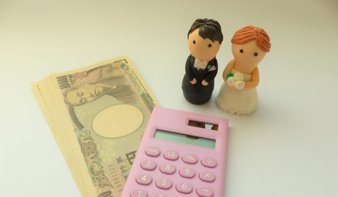 画像：電卓と一万円札と新郎新婦のフィギュア