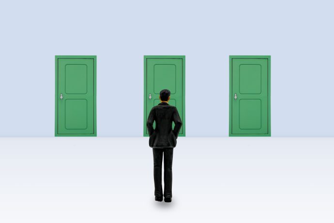 3つの並んだ緑のドアの目に立つ男性の写真