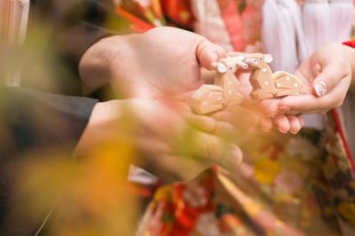 和装の花嫁と花婿の手のひらに乗った木でできた牛の置物の写真