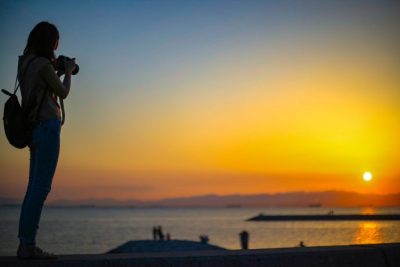 夕焼けに立つカメラマンのシルエットの写真