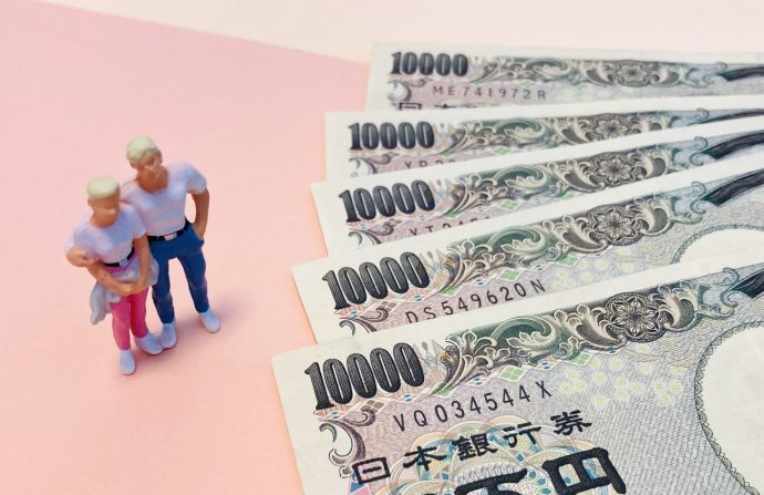 肩を組む男女のオブジェクトと一万円札の写真