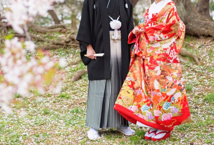紋付袴の新郎とそばに立つ色打掛の新婦