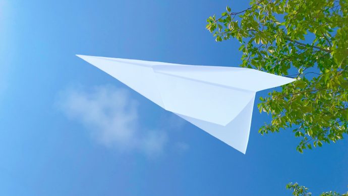 青空へ向かって飛ぶ紙飛行機