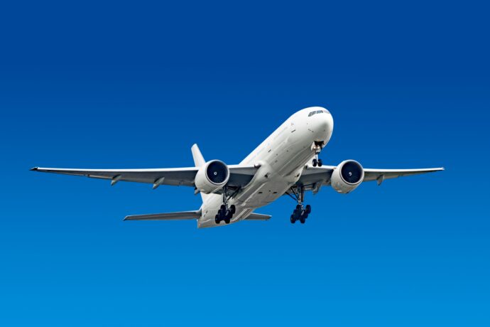 青空を背景に飛ぶ旅客機の画像