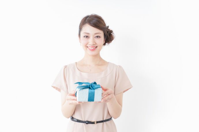 水色のリボンがかかったプレゼントボックスを差し出す女性の写真