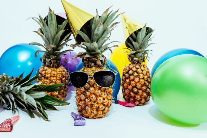画像：サングラスをかけたパイナップルとパーティーハットと風船