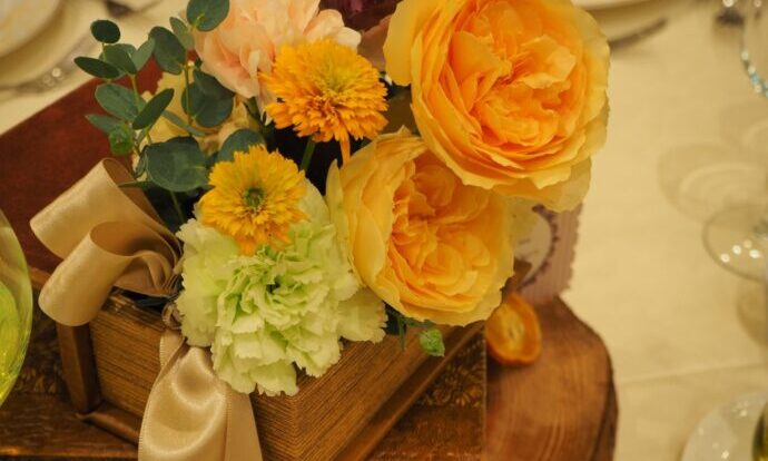画像：オレンジの装花と本型の置物