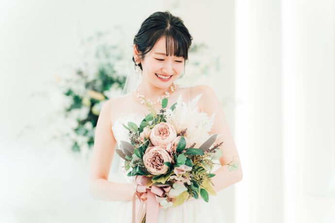 画像：ブーケを持ち伏し目がちに笑う花嫁の前撮り写真