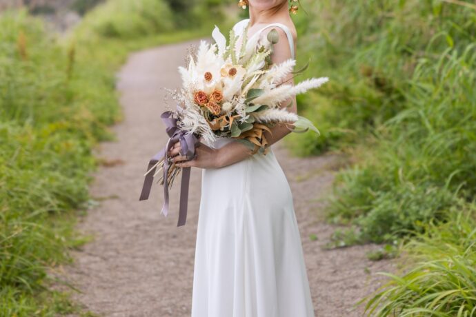 画像：花束を持って自然の中に立つ花嫁