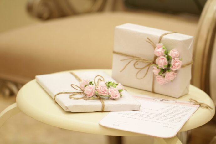 画像：白い包み紙で包装されピンクの花が飾られたプレゼントボックス