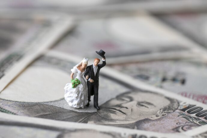 画像：敷かれた1万円札の上の花嫁と花婿のフィギュア