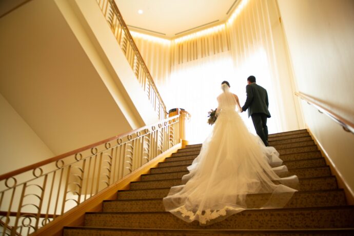 画像：階段で腕を組む新郎新婦の後ろ姿のウエディングフォト