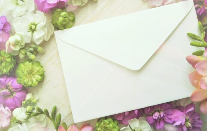 画像：花のリースに囲まれた白い封筒