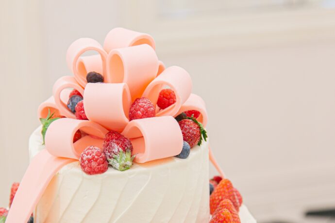 画像：ピンクのリボンの飾りが乗ったウエディングケーキ