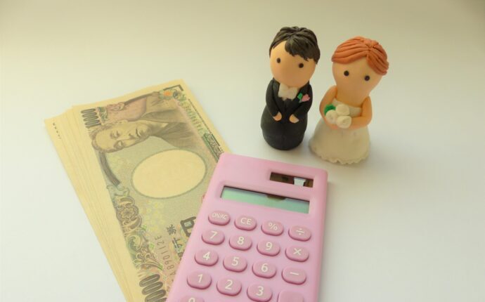 画像：電卓と1万円札と新郎新婦の人形
