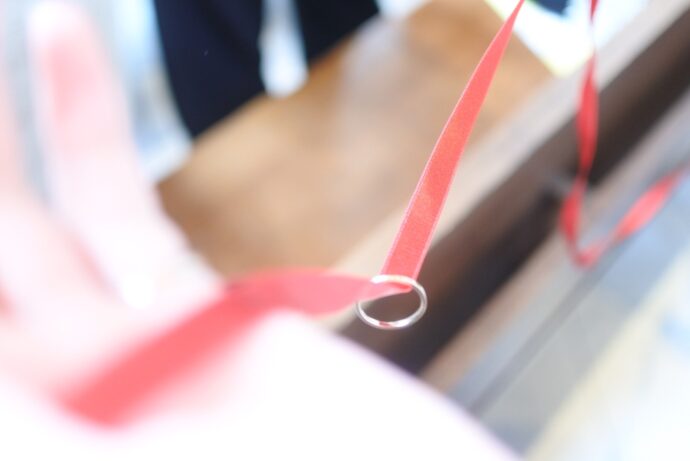 画像：赤いリボンに通された結婚指輪