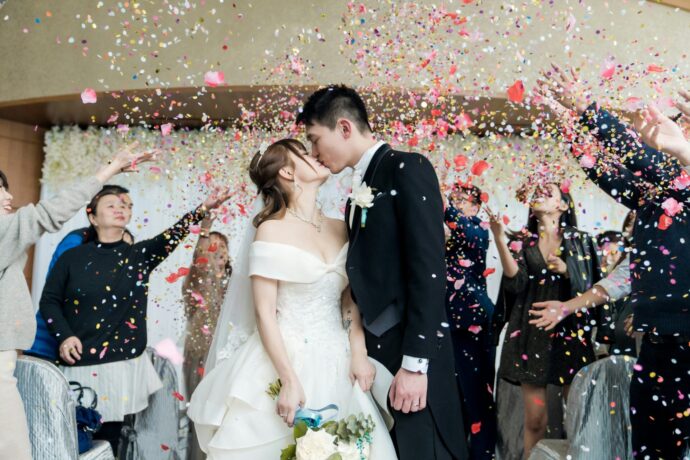 画像：コンフェッティの中キスを交わす花嫁と花婿