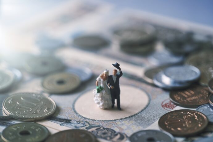 画像：日本円札と小銭の上に建つ花嫁と花婿のフィギュア