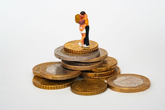 画像：コインのタワーの上で抱擁しキスするカップルの置物
