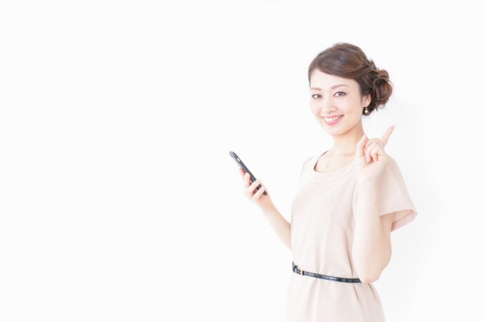 画像：白いパーティードレスを着て人差し指を立てる女性