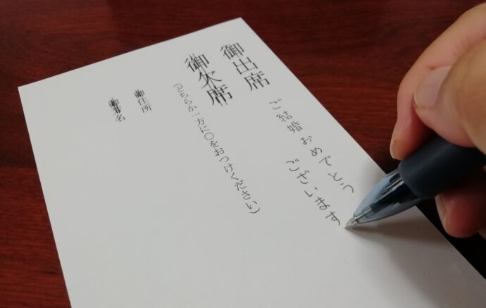 画像：返信ハガキに出席で連絡しようとしている