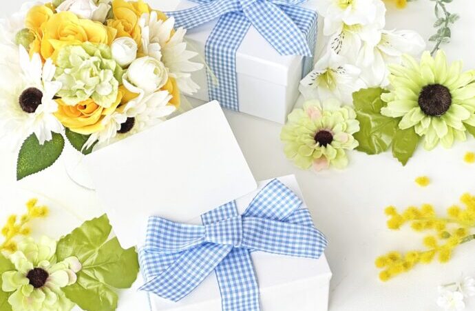 画像：黄色の花と水色のリボンがかけられた白いプレゼントボックス