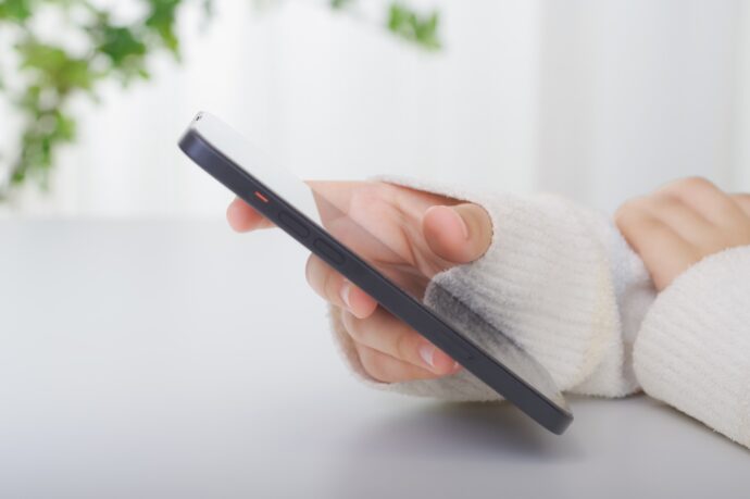 画像：スマートフォンをいじる女性の手元の写真