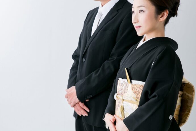 画像：黒留袖を着た女性の奥にダークスーツの男性が立っている
