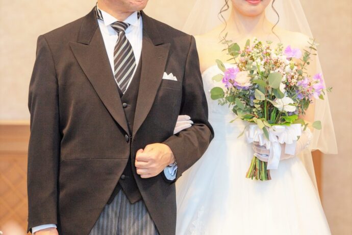 画像：花嫁と腕を組むモーニングコートを着た父親
