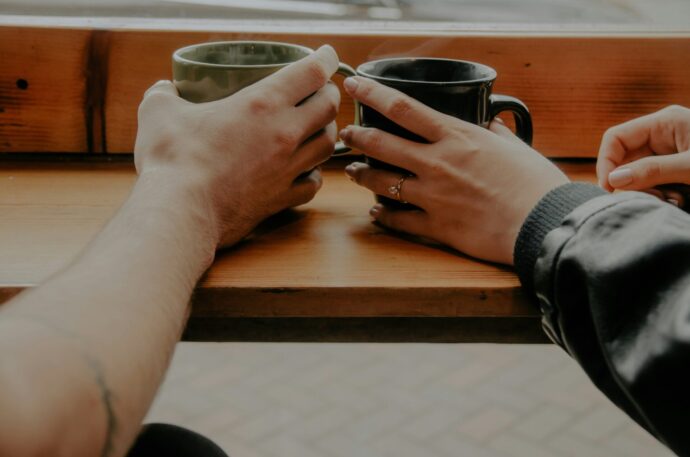 画像：マグカップを持ち隣同士に座る男女の手元