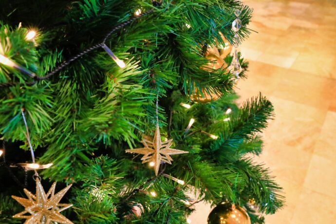画像：LEDの電飾とゴールドのオーナメントが下がったクリスマスツリーのアップ