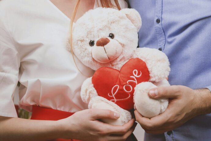 画像：LOVEと書かれたハートを抱える白い熊のぬいぐるみを持つ男女