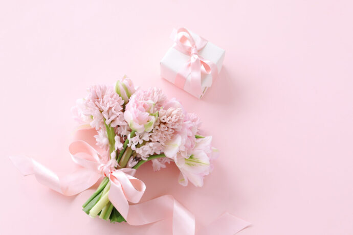 画像：ピンクの背景にピンクの花束とプレゼントボックス
