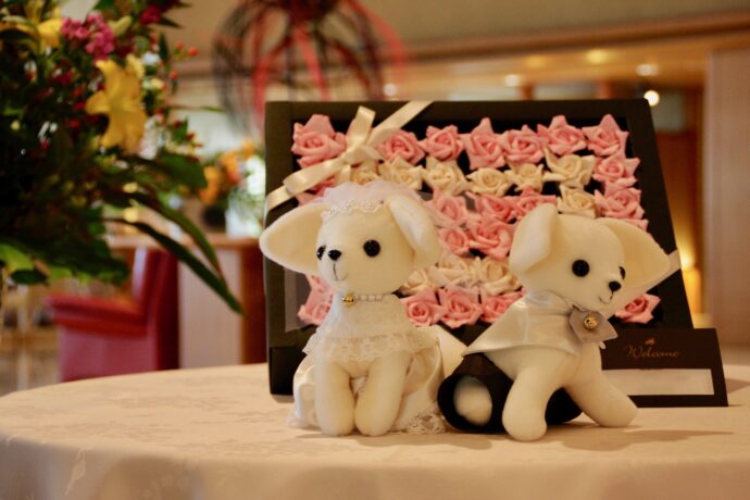 画像：婚礼衣装を着た白い犬のぬいぐるみとバラのボード
