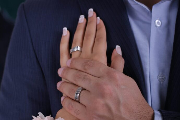 画像：男性の胸に当てている結婚指輪をした左手とその手を上から抑える結婚指輪をした男性の左手