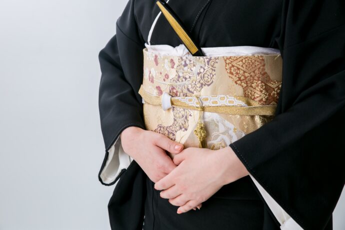 画像：お腹の前で手を重ねる黒留袖の女性