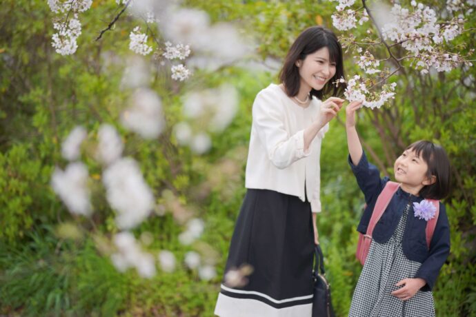 画像：ランドセルの女の子と桜をいじる女性
