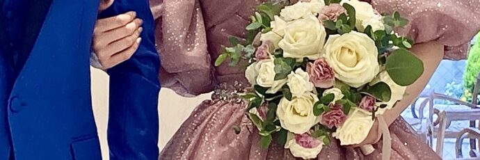 画像：バラのブーケを持った花嫁と腕を組む花婿