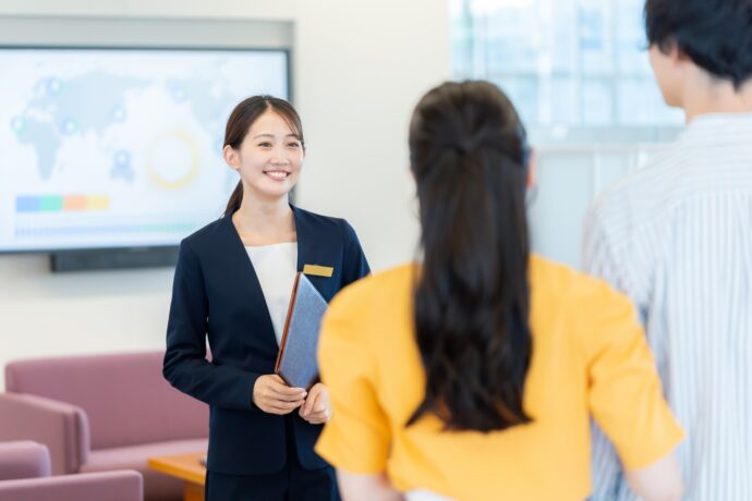 画像：若い男女を案内する女性