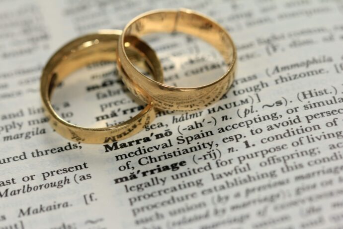 画像：英字新聞の上に置かれたゴールドの結婚指輪