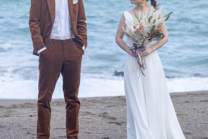 画像：ビーチに立つラフな格好の新郎新婦