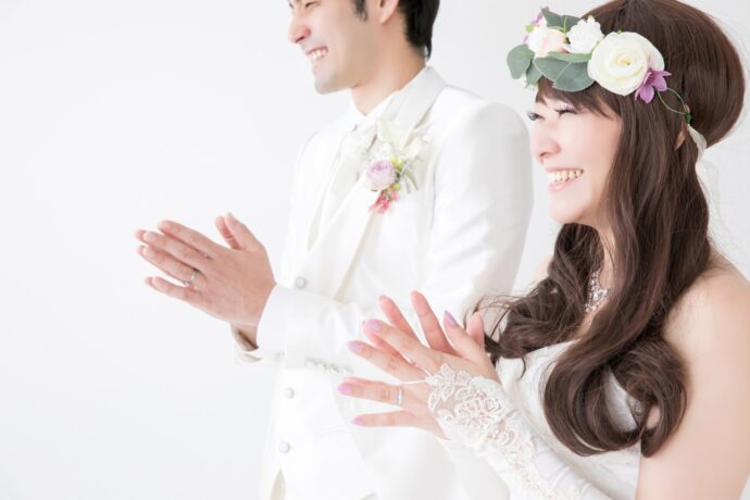 画像：笑顔で手拍子する新郎新婦